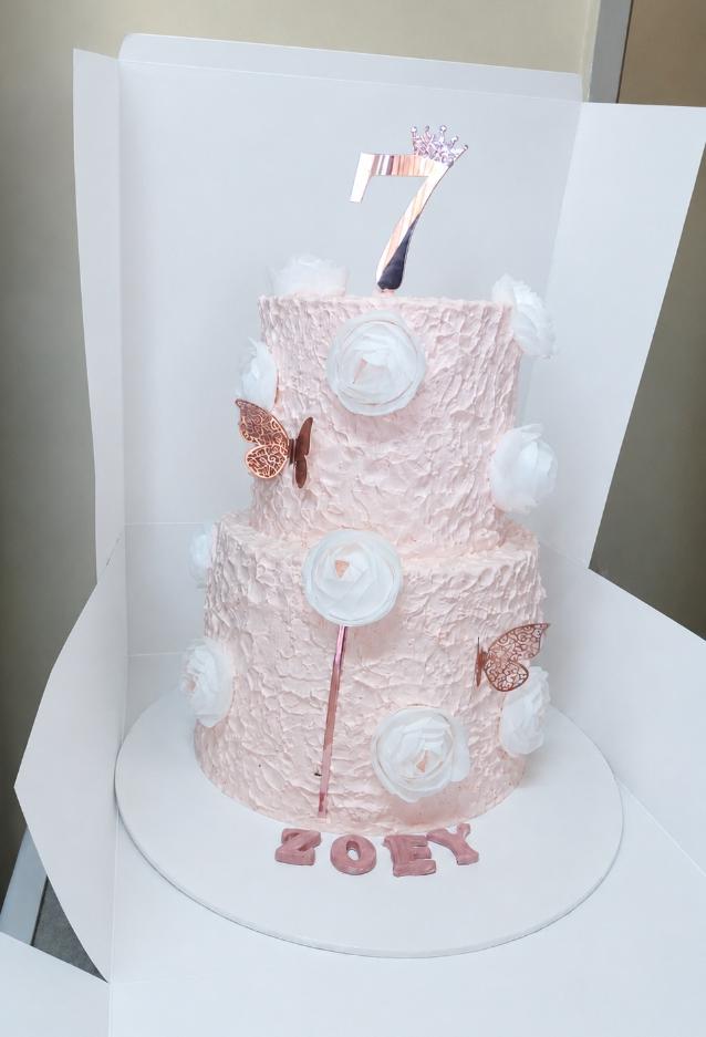 Pink two tier birthday cake with white roses and butterflies for a 7th birthday