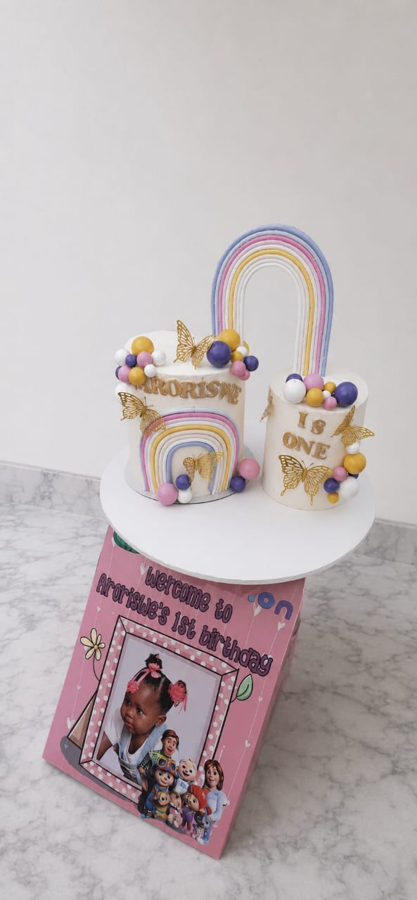 Rainbow first birthday cake with butterflies and pastel decorations