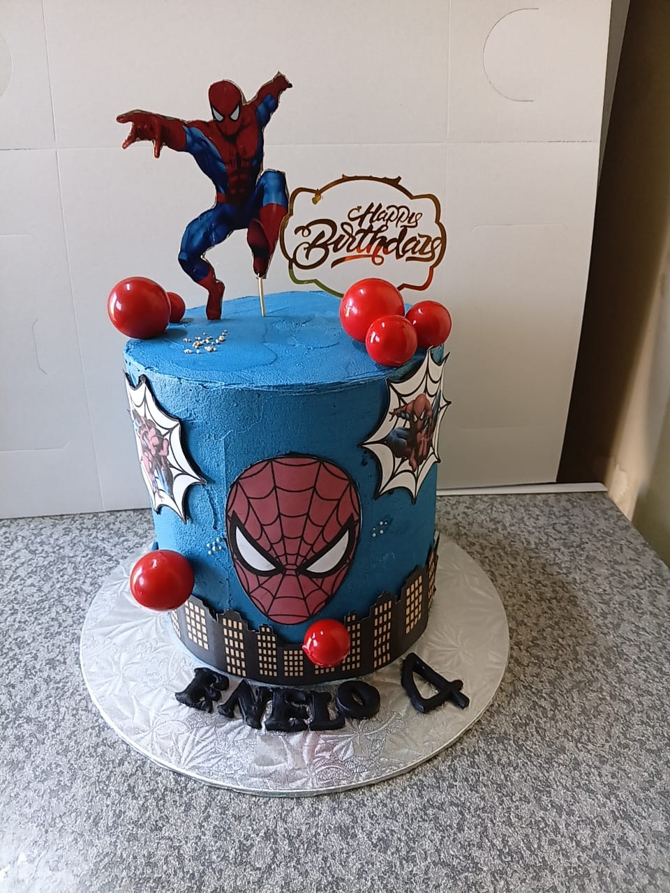 Blue Spiderman birthday cake with city skyline and red decorations